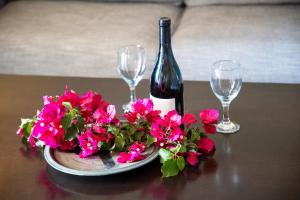 a bottle of wine and flowers on a table with glasses at Nest Aegina Apartments in Perdika