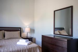 a bedroom with a bed with a mirror and a dresser at Nest Aegina Apartments in Perdika