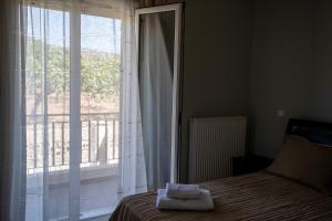 a bedroom with a bed and a large window at Nest Aegina Apartments in Perdika