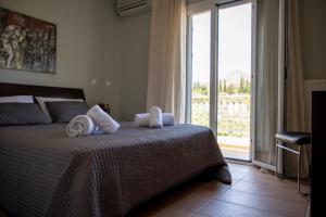 een slaapkamer met een bed en een groot raam bij Nest Aegina Apartments in Perdhika