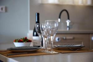 a table with two glasses and plates and wine bottles at Nest Aegina Apartments in Perdika