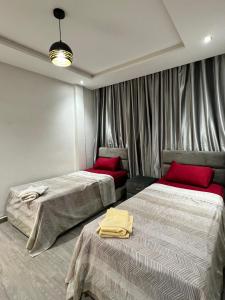 - une chambre avec 2 lits dotés d'oreillers rouges dans l'établissement SUNFLOWER Apartments, à Agadir nʼ Aït Sa
