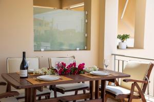 a dining room table with chairs and a bottle of wine at Nest Aegina Apartments in Perdika