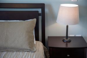a lamp sitting on a table next to a bed at Nest Aegina Apartments in Perdika