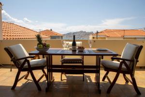 een tafel met stoelen en een fles wijn op een patio bij Nest Aegina Apartments in Perdhika