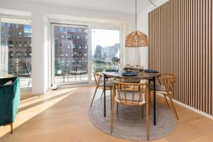 a dining room with a table and chairs and a large window at Lys 3 værelses lejlighed med 26 m2 sydvendt altan in Aarhus