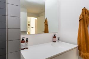La salle de bains blanche est pourvue d'un lavabo et d'un miroir. dans l'établissement Lys 3 værelses lejlighed med 26 m2 sydvendt altan, à Aarhus