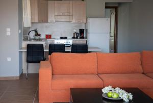 a living room with an orange couch and a kitchen at Nest Aegina Apartments in Perdika
