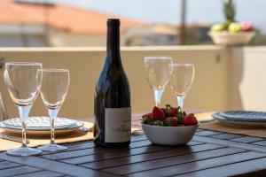 a bottle of wine and glasses on a table with strawberries at Nest Aegina Apartments in Perdika