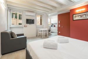 ein Schlafzimmer mit einem Bett, einem Stuhl und einem TV in der Unterkunft Vicolo Zini Apartments in Verona