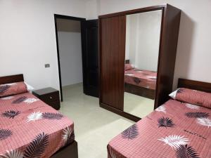 a bedroom with two beds and a mirror at شاليه 120/202 مارينا دلتا in Al Ḩammād