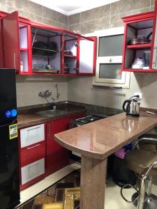 uma cozinha com armários vermelhos e uma bancada em شاليه 120/202 مارينا دلتا em Al Ḩammād