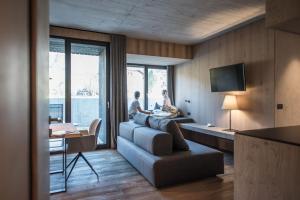 two people sitting in a living room with a couch at Hotel Krondlhof in Brunico