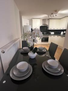 a dining room table with plates and a vase of flowers at PRECIOUSHOUSELUXURYSTAY in London