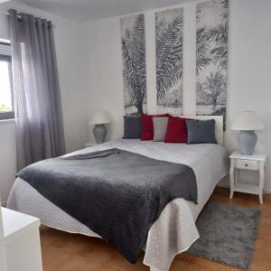 - une chambre avec un grand lit et des oreillers rouges dans l'établissement Apartamentos Bela Vista, à Nazaré