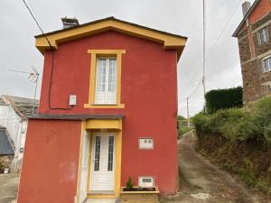 una casa roja con una puerta blanca y una ventana en Villa Maribel, en Foz