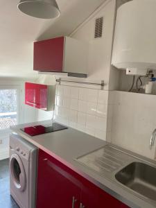 a kitchen with red cabinets and a washing machine at Chez Emmanuel in Saintes