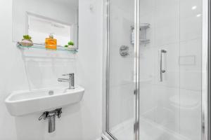 Un baño blanco con lavabo y ducha. en Piccadilly Haven, Flat in London VR12, en Londres