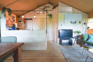 a living room with a tv and a couch at Glamping Safarilodge 'Grutte Fiif' met airco, extra keuken op veranda en privé achtertuin in Grou
