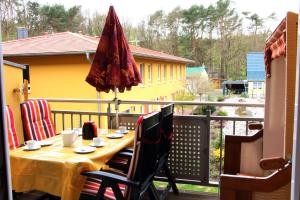 a table on a balcony with a yellow house at Strandläufer Zempin in Zempin