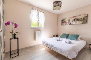 Les Lilas Confort & Nature في فولفيك: غرفة نوم مع سرير أبيض كبير مع وسائد زرقاء