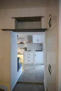 a kitchen with white cabinets and a hallway at mikro Thama in Kámbos