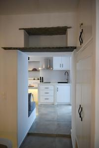 una cocina con armarios blancos y un pasillo en mikro Thama en Kámbos