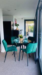 a dining room with a table and green chairs at Luxury beach front rooms- PMA in Kirkcaldy