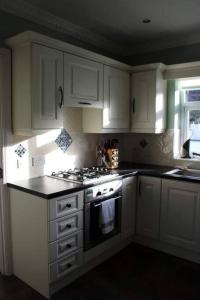 a kitchen with white cabinets and a stove top oven at Baile Go Deo. in Falcarragh