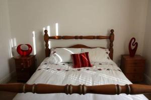 1 dormitorio con cama de madera y almohadas rojas en Baile Go Deo., en Falcarragh