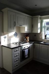a kitchen with white cabinets and a stove top oven at Baile Go Deo. in Falcarragh