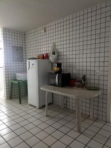 cocina con mesa y nevera en Cantinho para mulheres, en Parnaíba