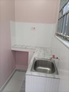 eine weiße Küche mit einem Waschbecken und einem Fenster in der Unterkunft Pearl furnished residence in Buloba