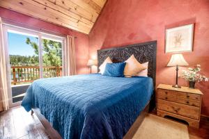 um quarto com uma cama com um edredão azul e uma janela em Boulder Bay Park Lakefront - Across the street from the lake and Boulder Bay Park! Hot tub! em Big Bear Lake