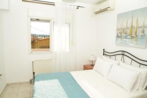 a white bedroom with a bed and a window at Unique Home in Kanoni