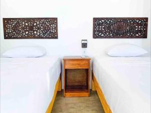 two beds in a room with a nightstand between them at Villa Ocean in Puerto Escondido