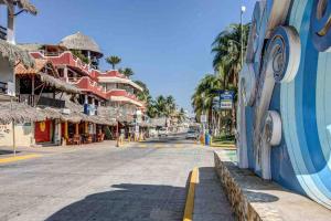 een lege straat in een stad met palmbomen en gebouwen bij Villa Ocean in Puerto Escondido