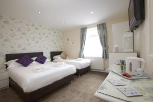 a hotel room with two beds and a desk at The Bayridge Guest House in Bridlington