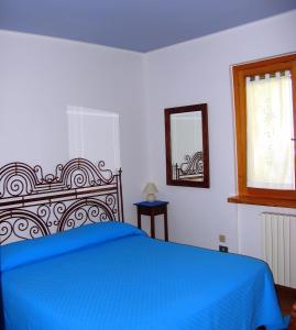 a bedroom with a blue bed and a mirror at La Casa Dei Boschi in San Marino