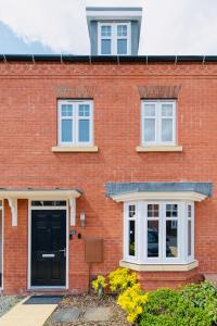uma casa de tijolos vermelhos com uma porta preta e janelas em Rugby Modern 3 Bed 6 guest house em Clifton upon Dunsmore