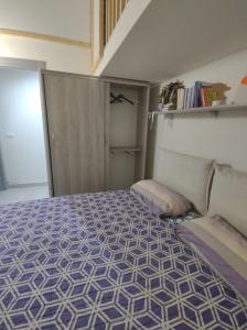1 dormitorio con 1 cama con edredón morado y blanco en Nina Apartment, en Mondragone
