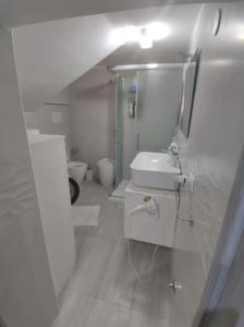 Baño blanco con lavabo y espejo en Nina Apartment, en Mondragone