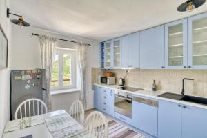 une cuisine avec des placards bleus et une table avec des chaises dans l'établissement Eva's country house, à Buljarica