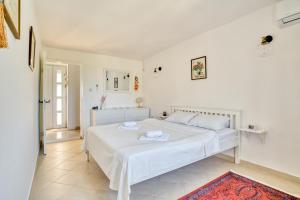 a white bedroom with a bed and a bathroom at Eva's country house in Buljarica