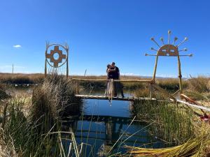 dos personas de pie en un puente sobre un estanque con un molino de viento en Uros Lodge Lover Titiqaqa, en Puno