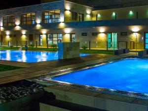 a large swimming pool in front of a building at night at Almazara Suites in Alcalá del Júcar