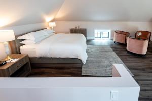 Un dormitorio con una gran cama blanca y una mesa en The Glenerin Inn, en Mississauga