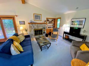 a living room with a blue couch and a fireplace at FC20 Comfortable Forest Cottage home - AC, great for kids, lots of yard space! Walk to the slopes! in Bretton Woods