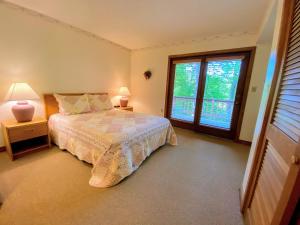 1 dormitorio con 1 cama, 2 lámparas y ventana en FC20 Comfortable Forest Cottage home - AC, great for kids, lots of yard space! Walk to the slopes!, en Bretton Woods