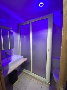 La salle de bains est pourvue d'un lavabo et de toilettes avec des lumières violettes. dans l'établissement Spacious appartement of two rooms close to morocco mall, à Casablanca